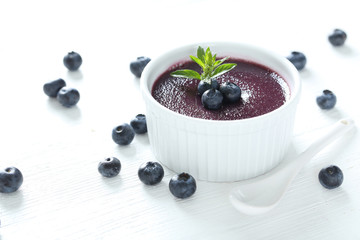 Delicious blueberry mousse in bowl on wooden table