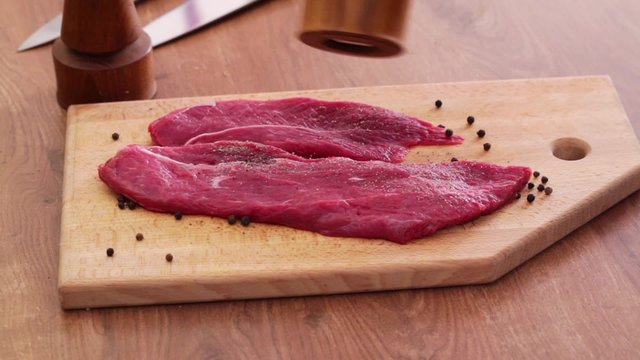 HD 1080 close up: beef steak slices seasoned with black pepper using pepper grinder 