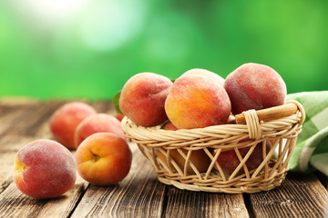 Ripe peaches fruit in basket on a brown wooden background