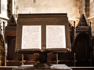 details of a gregorian chant open on a wooden music stand
