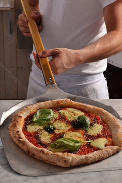 Cocinero sacando la pizza del horno.