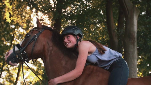 Girl leaning lovingly on her horse while riding in nature