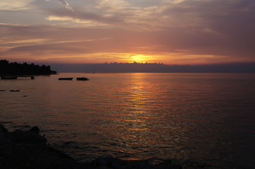 Fototapeta na wymiar beautiful sunset at seaside with silhouette of boats horizontally cropped
