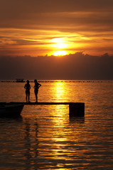 Fototapeta premium sea and pier at a beautiful sunset with a silhouette of people