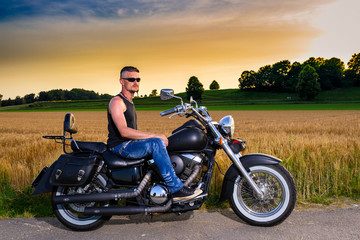 Tough guy with his bike in front of a corn field