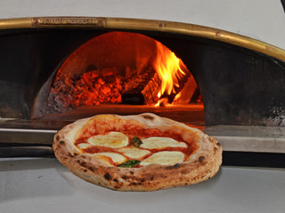 Sacando la pizza del horno a leña.
