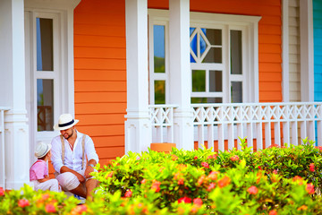 cute father and son sitting and talking on porch, caribbean street