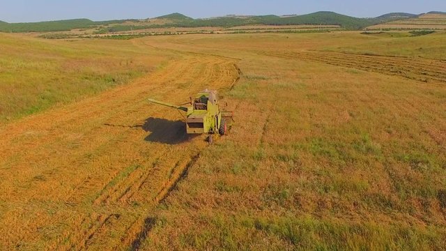 AERIAL VIEW. Small farms.Old combine harvesting. 