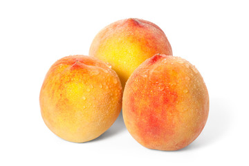Three ripe peach with drops of water on a white background