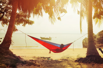 One man looking on the sea in hammock on a beach at sunset.Vintage effect added for create...