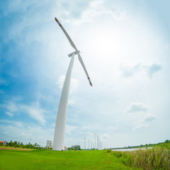 Fototapeta premium White wind turbine generating electricity on blue sky