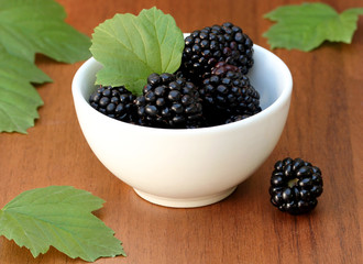 Gigantic blackberries in a white bowl on a wooden table
