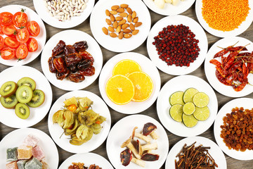 Different products on saucers on wooden table, top view