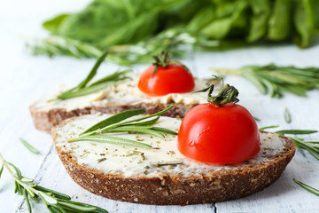 Delicious sandwiches with tomatoes and greens on table close up
