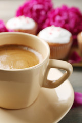 Composition with cup of coffee, muffins and peony flowers on wooden background