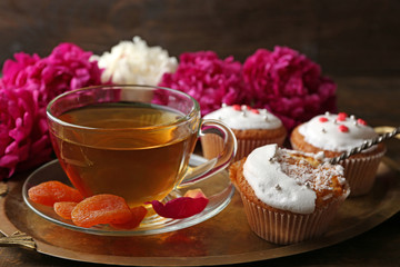 Composition with cup of herbal tea, dried apricots and peony flowers on dark wooden background