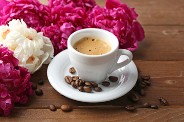 Composition with cup of coffee and peony flowers on wooden background