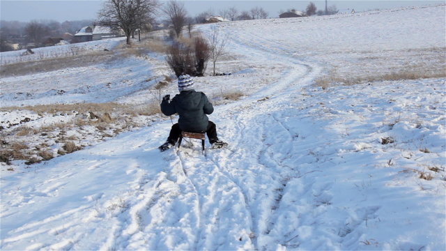 sled through the snow/from the mountain on a sled boy busy on snow in winter