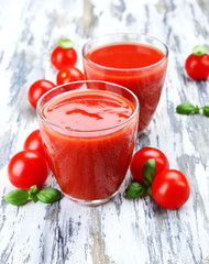 Glasses of tomato juice with vegetables on wooden background