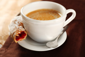 Cup of coffee with cookie on table, closeup