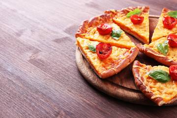 Slices of tasty cheese pizza with basil and cherry tomatoes on table close up