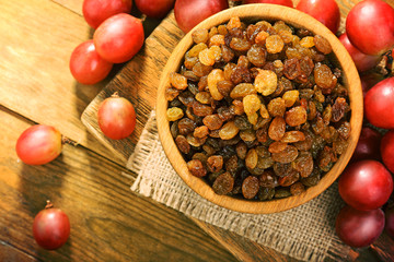 Raisins in bowl with grapes on table close up