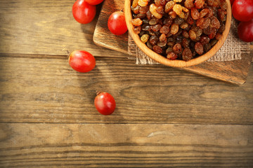 Raisins in bowl with grapes on table close up