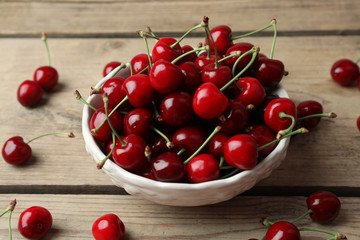 Sweet cherries in bowl on wooden table close up