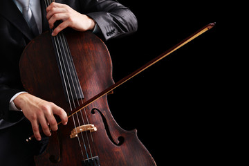 Man playing on cello on dark background