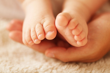 Adult hands holding baby feet, closeup