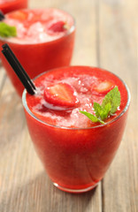 Glasses of strawberry smoothie with berries on table close up