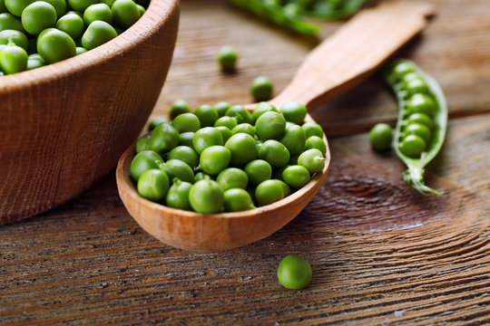 Fresh green peas in bowl and spoon on table close up