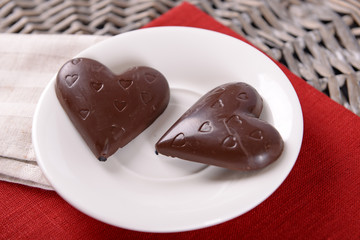 Chocolate heart shaped candies on sticks in white plate, closeup