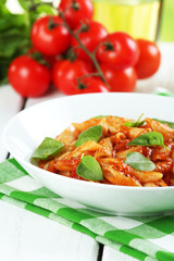 Pasta with tomato sauce and basil on table close up