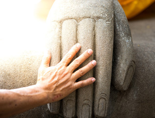 Main humaine et main de statue de bouddha
