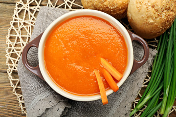 Carrot cream-soup with buns on table close up