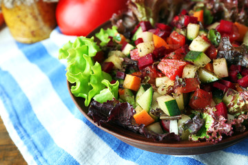 Wooden bowl of fresh vegetable salad on table, closeup