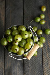 Green gooseberry in pail on wooden background
