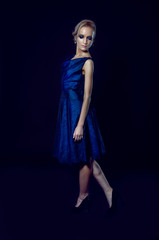 Studio portrait of beautiful blonde woman in dark blue dress