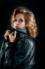 Studio portrait of blonde woman in leather biker jacket.