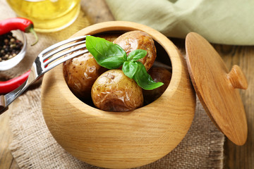 Baked potatoes in bowl on wooden table, closeup