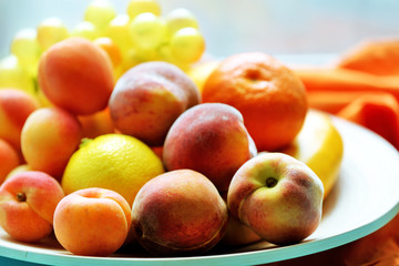 Heap of fresh fruits on tray on wooden table close up