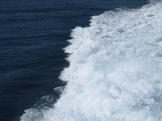 Trail on water surface behind of fast moving ferryboat