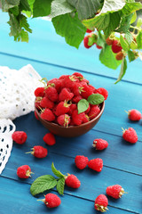 Fresh raspberries in bowl on blue wooden background