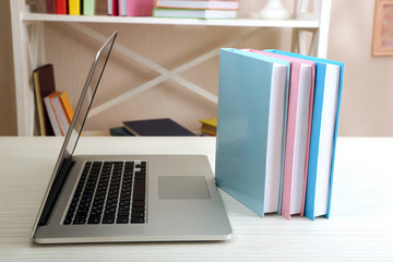 Stack of books with laptop on table in room