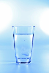 Pill in glass of water on light background