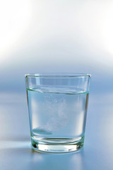 Pill in glass of water on light background