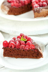 Piece of cake with chocolate Glaze and raspberries on color wooden background
