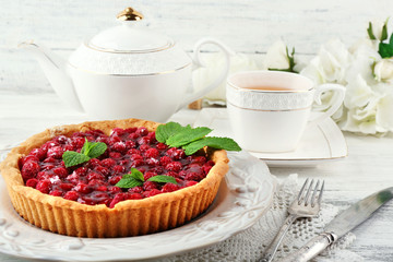 Tart with raspberries and tasty tea, on color  wooden background
