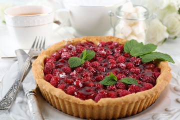 Tart with raspberries and tasty tea, on color  wooden background